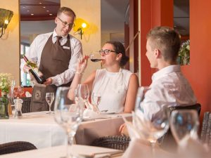 Frau bei der Weinprobe im Restaurant La Vie im Hotel Schwarzwald Panorama während der Kellner den Gästen den Wein präsentiert