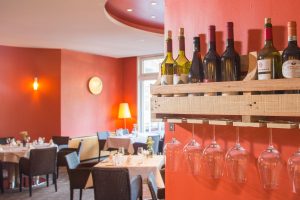 in warmen Farben gestaltetes Restaurant im Hotel Schwarzwald Panorama mit gedeckten Tischen und Blick auf ein Weinregal