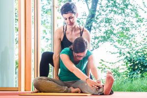 Selfness Leiterin Kerstin Weinbrecht während der Hilfestellung bei einer Yoga Übung mit einem Gast des Schwarzwald Panoramas