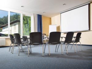 An ensemble of chairs in a conference room equipped with a projector and a flipchart, as part of the conference services at the conference hotel SCHWARZWALD PANORAMA