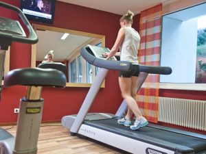 A woman working out on a treadmill in one of the fitness rooms at the hotel SCHWARZWALD PANORAMA