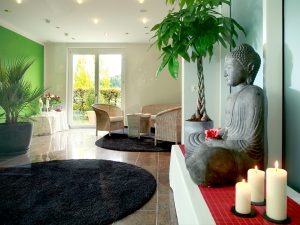 A relaxing room with a stone-made buddha statue and some candles next to it, at the wellness hotel SCHWARZWALD PANORAMA