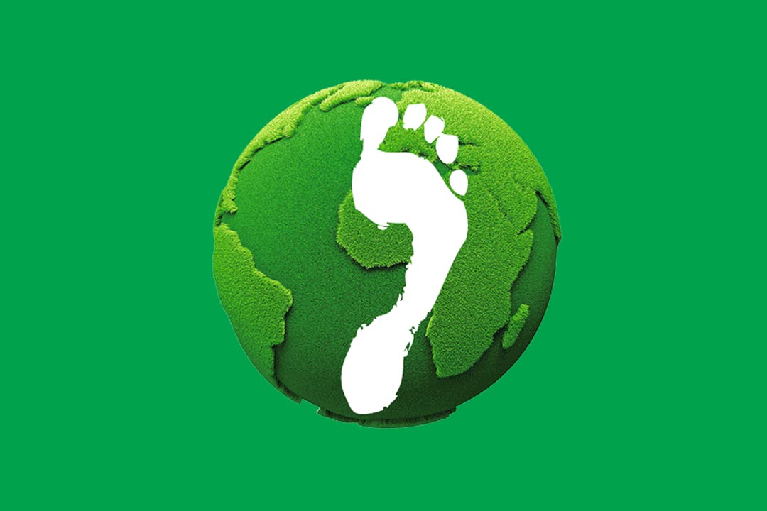 Ein weißer Fußabdruck, auf einer grünen Erde. Symbolisch für den CO2 Fußabdruck den ein klimaneutraler Urlaub verringert
