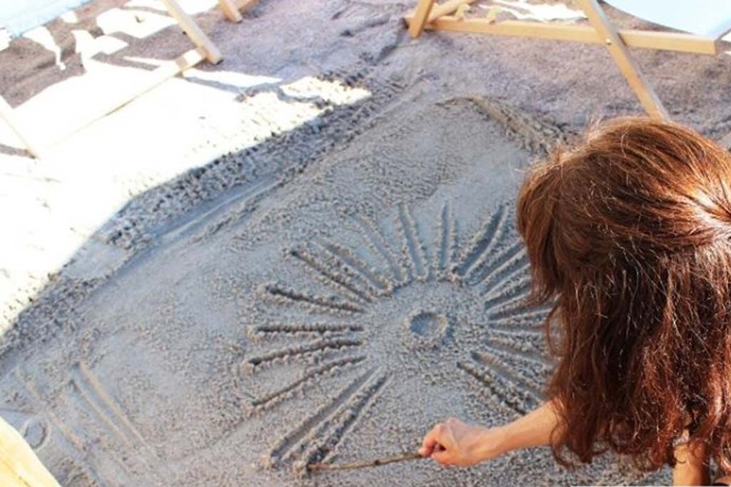 Frau zeichnet ein Sonnensymbol in den Sand im Wellnessbereich des Selfness Hotel SCHWARZWALD PANORAMA